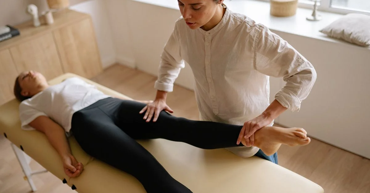 Un fisioterapeuta asiste a una mujer con terapia de rehabilitación de la pierna en una sala de tratamiento tranquila.