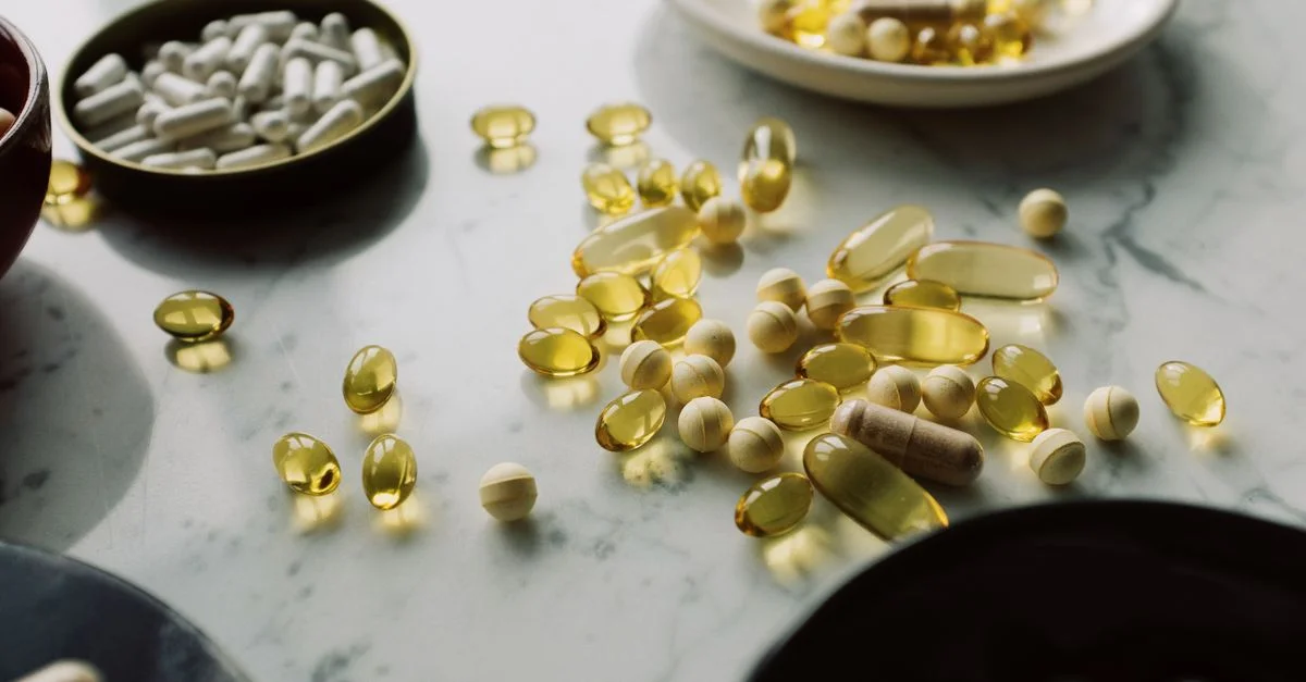 Un primer plano de diversas píldoras y suplementos dispuestos sobre una superficie de mármol, destacando temas de salud y bienestar.